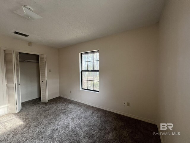 unfurnished bedroom featuring a closet, carpet, and a textured ceiling