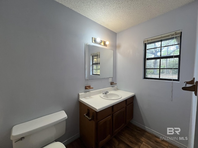 bathroom featuring vanity, wood-type flooring, toilet, and a textured ceiling