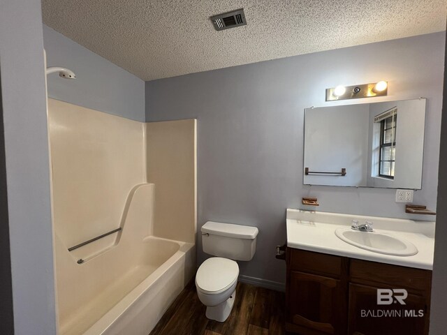 full bathroom with toilet, a textured ceiling, shower / bathtub combination, vanity, and hardwood / wood-style floors