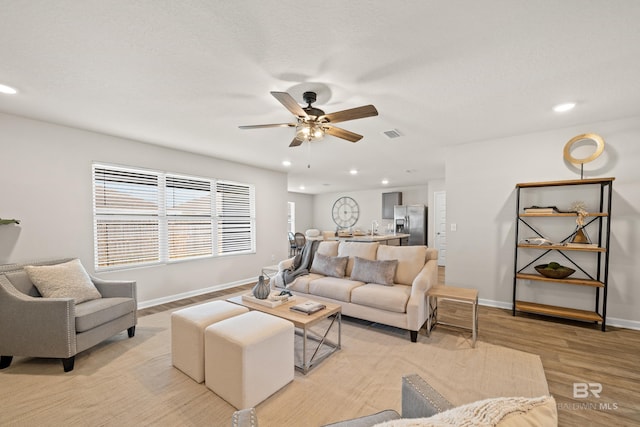 living room featuring ceiling fan and light hardwood / wood-style flooring