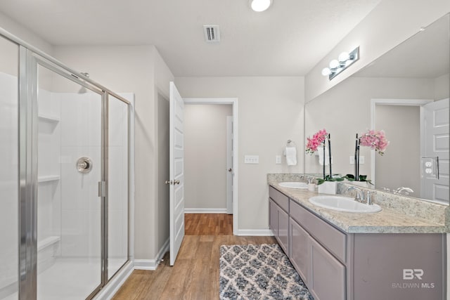 bathroom with hardwood / wood-style floors, vanity, and a shower with shower door