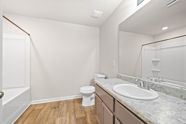 full bathroom featuring bathing tub / shower combination, hardwood / wood-style floors, a textured ceiling, toilet, and vanity