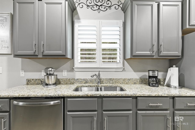 kitchen featuring light stone counters, sink, stainless steel dishwasher, and gray cabinets