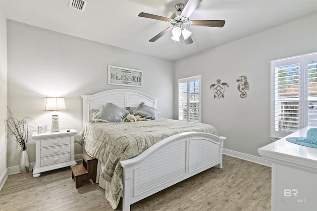 bedroom with ceiling fan, multiple windows, and light hardwood / wood-style floors