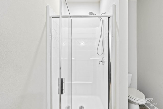 bathroom with toilet and a shower with shower door