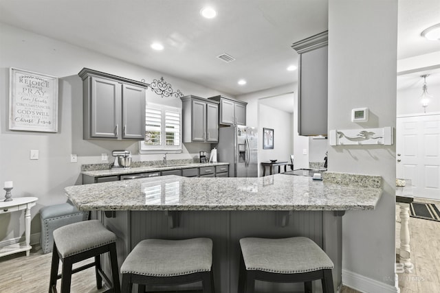 kitchen with kitchen peninsula, sink, light hardwood / wood-style flooring, gray cabinetry, and stainless steel fridge