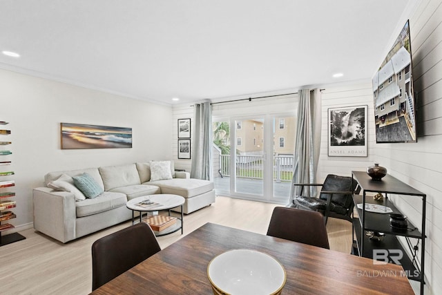 living room with crown molding, wood walls, and light hardwood / wood-style flooring