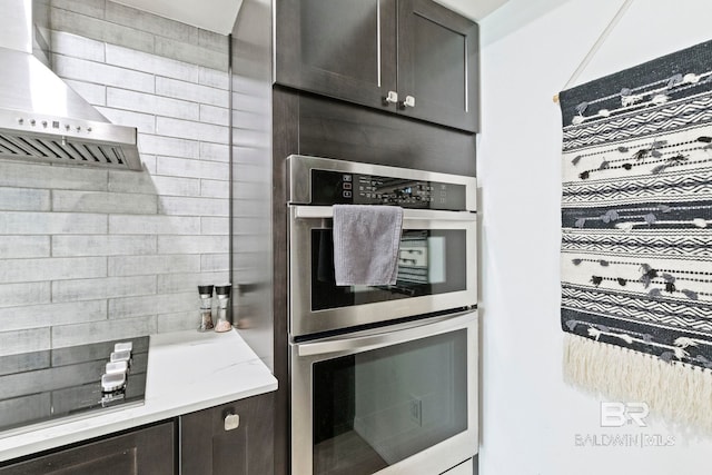 kitchen featuring stainless steel double oven, wall chimney exhaust hood, and dark brown cabinetry