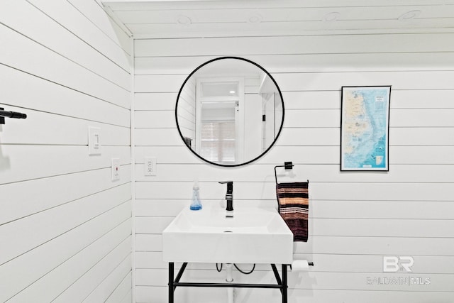 bathroom featuring wood walls and sink