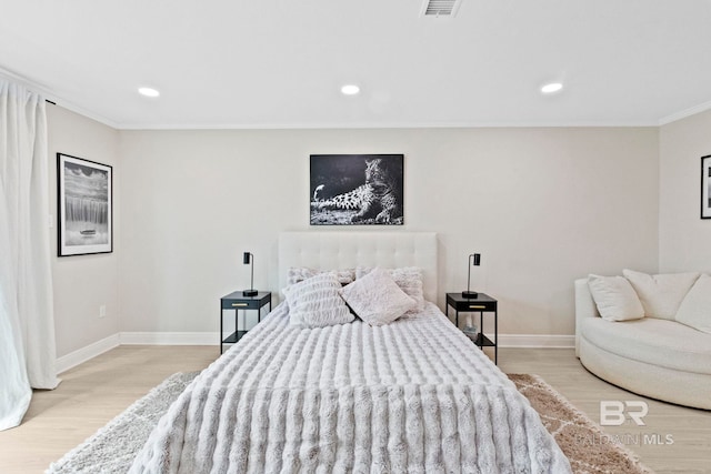 bedroom with ornamental molding and light hardwood / wood-style floors