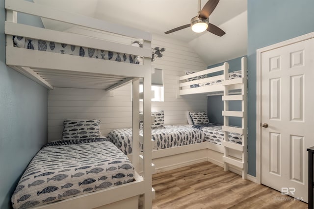 2802 Bienville Blvd, Dauphin Island, AL 36528 - bedroom with ceiling fan, wood walls, vaulted ceiling, and light wood-type flooring