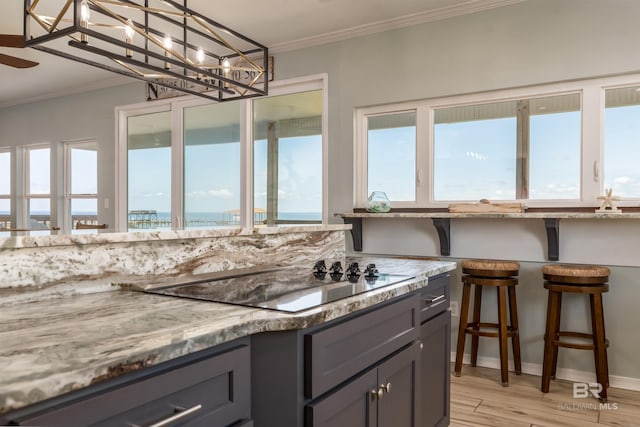 2802 Bienville Blvd, Dauphin Island, AL 36528 - kitchen with gray cabinets, crown molding, black electric cooktop, light stone counters, and light wood-style flooring
