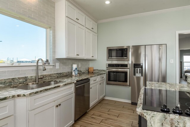 2802 Bienville Blvd, Dauphin Island, AL 36528 - kitchen with decorative backsplash, ornamental molding, white cabinetry, a sink, and stainless steel appliances