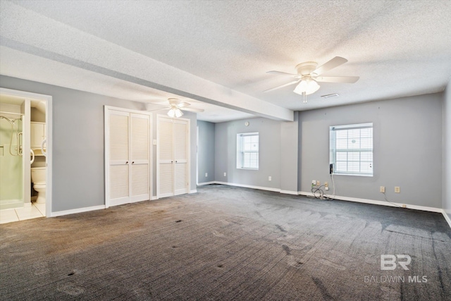 unfurnished bedroom featuring ensuite bathroom, multiple closets, a textured ceiling, ceiling fan, and light carpet