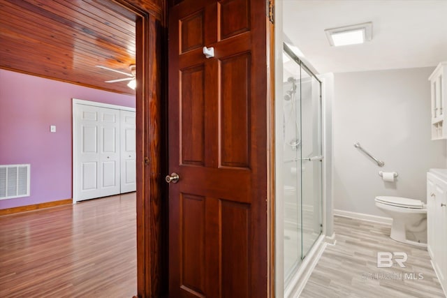 bathroom featuring ceiling fan, wood-type flooring, toilet, vanity, and an enclosed shower