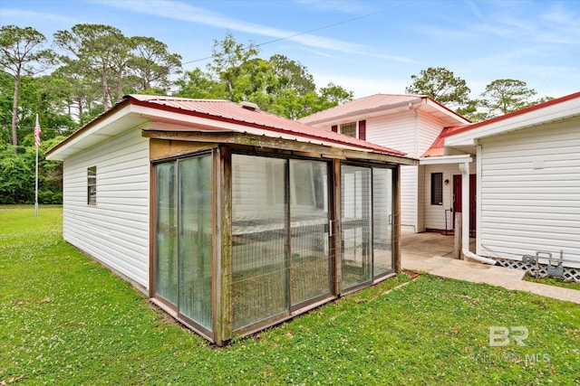 view of outbuilding with a lawn and a sunroom