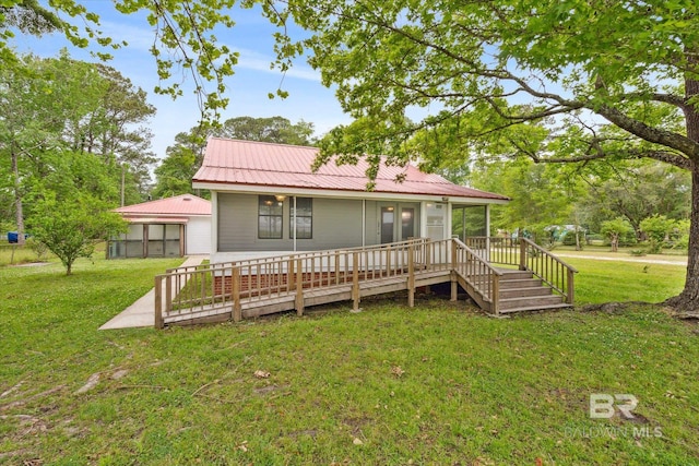 back of property with a wooden deck, a lawn, and a sunroom