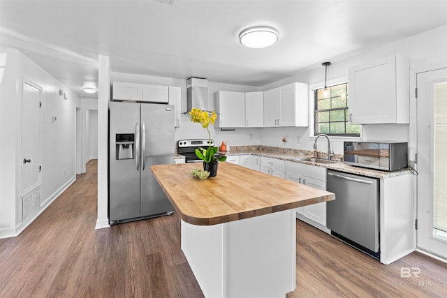 kitchen featuring appliances with stainless steel finishes, white cabinets, a kitchen island, sink, and hardwood / wood-style flooring