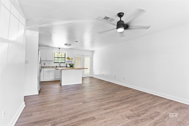 unfurnished living room with hardwood / wood-style floors, sink, and ceiling fan