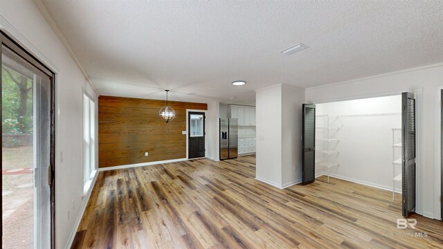 7770 Simmons Dr, Foley, AL 36535 - unfurnished living room with light wood-type flooring, a textured ceiling, baseboards, and wooden walls