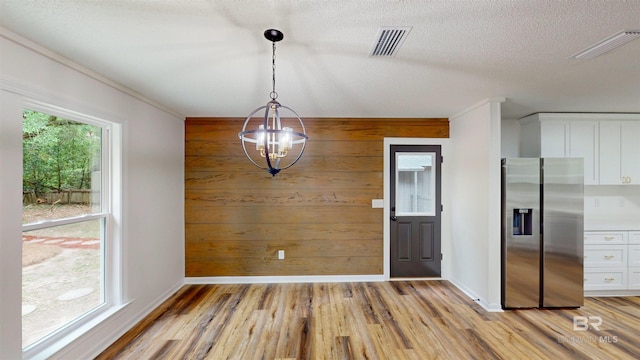 7770 Simmons Dr, Foley, AL 36535 - unfurnished dining area with light wood-style floors, baseboards, ornamental molding, a textured ceiling, and wood walls