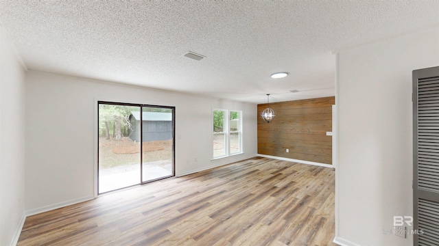7770 Simmons Dr, Foley, AL 36535 - unfurnished room featuring light wood-style flooring, wood walls, a textured ceiling, baseboards, and a chandelier