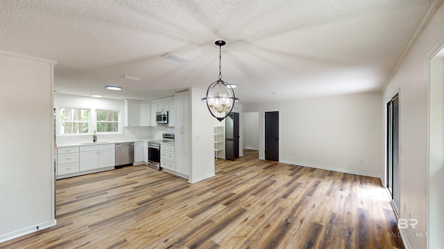 7770 Simmons Dr, Foley, AL 36535 - kitchen featuring stainless steel appliances, a sink, light wood-style flooring, open floor plan, and a textured ceiling