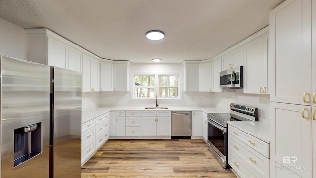 7770 Simmons Dr, Foley, AL 36535 - kitchen with stainless steel appliances, a sink, light countertops, white cabinets, and a textured ceiling