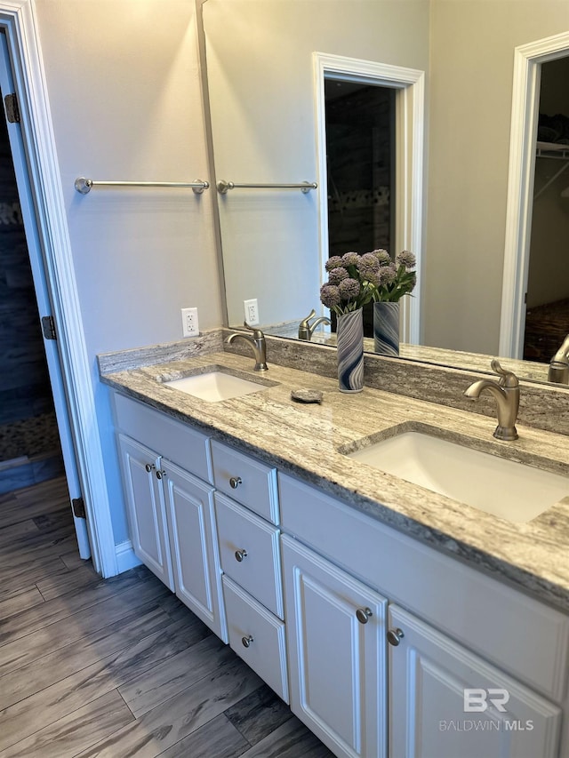 full bath with double vanity, wood finished floors, and a sink