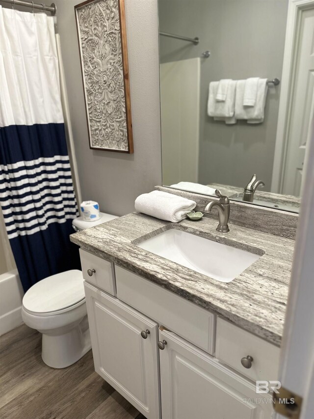 bathroom featuring vanity, shower / bath combination with curtain, wood finished floors, and toilet