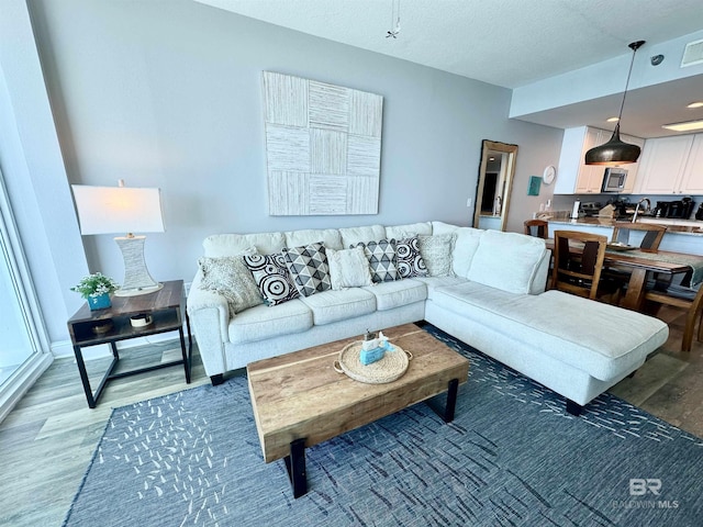 living area featuring a textured ceiling, light wood-type flooring, and visible vents