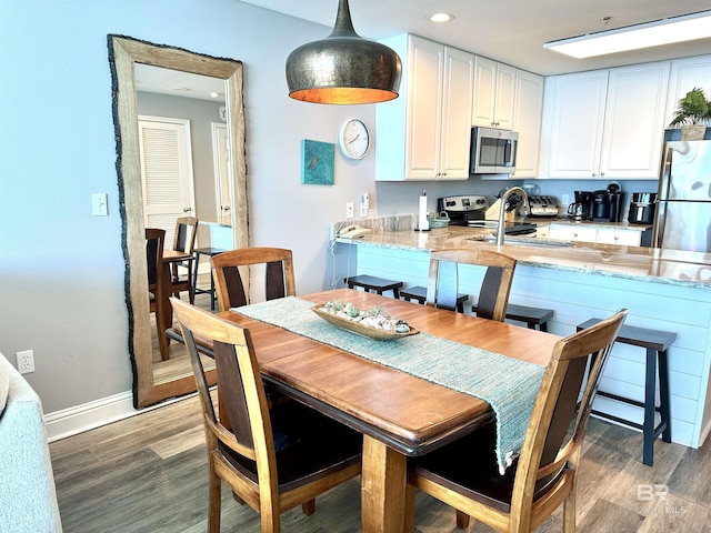 kitchen with a sink, appliances with stainless steel finishes, wood finished floors, and white cabinetry