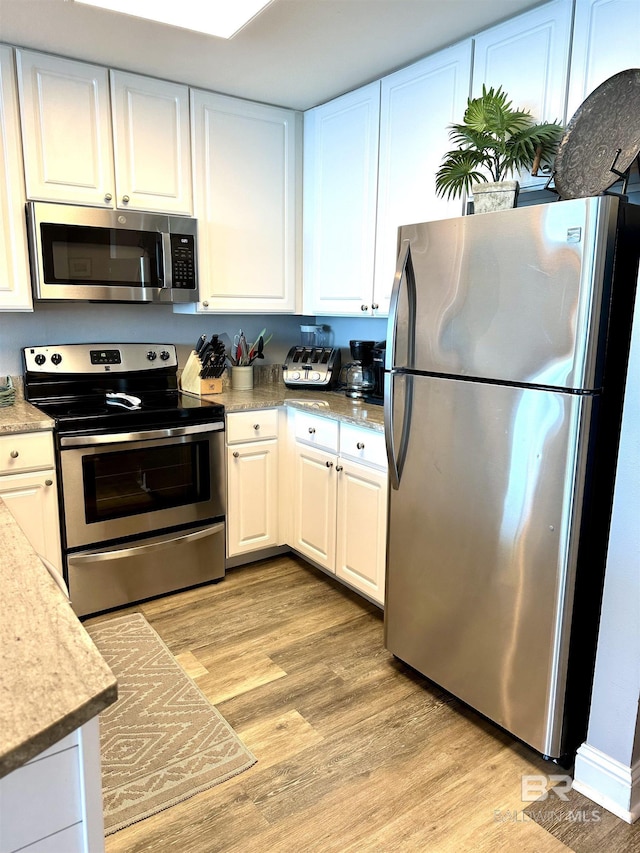 kitchen with stainless steel appliances, light wood-type flooring, and white cabinets