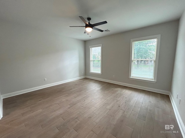 spare room featuring dark wood-style flooring, visible vents, baseboards, and ceiling fan