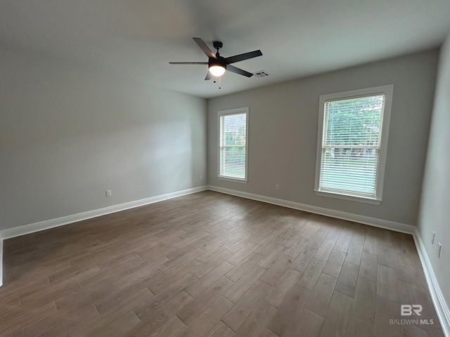 spare room with baseboards, visible vents, a ceiling fan, and dark wood-style flooring
