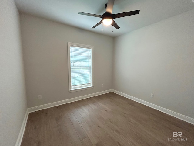 empty room featuring dark wood-style floors, baseboards, and ceiling fan