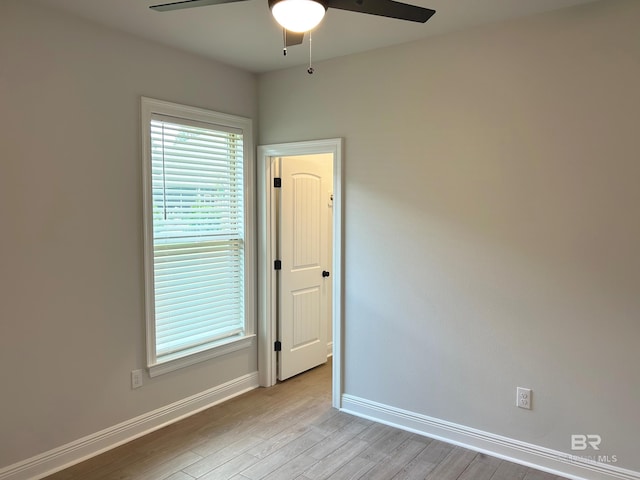 empty room featuring a ceiling fan, baseboards, and light wood finished floors