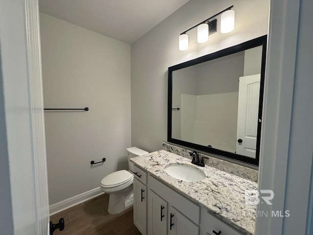 bathroom featuring wood finish floors, vanity, toilet, and baseboards