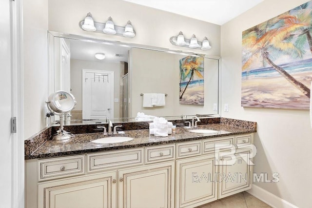 bathroom with a sink, baseboards, double vanity, and tile patterned flooring