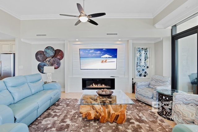 living area featuring visible vents, a lit fireplace, and crown molding