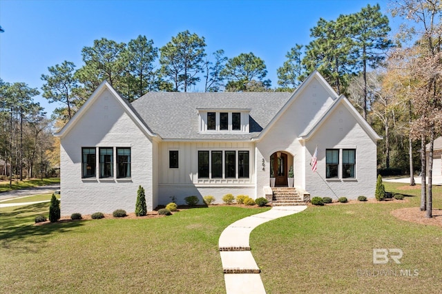 view of front facade with a front lawn, brick siding, board and batten siding, and a shingled roof