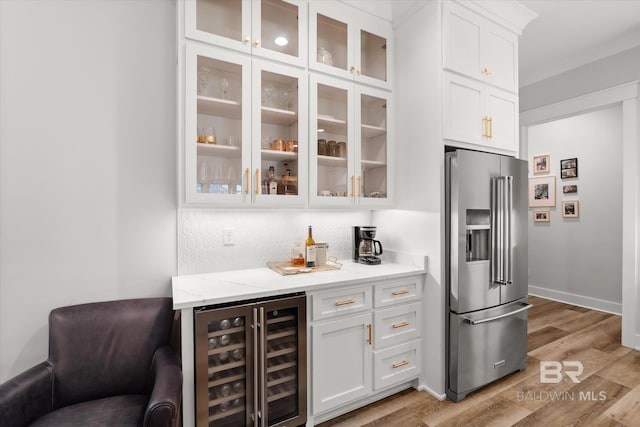 bar featuring tasteful backsplash, wine cooler, a dry bar, light wood-type flooring, and high end fridge