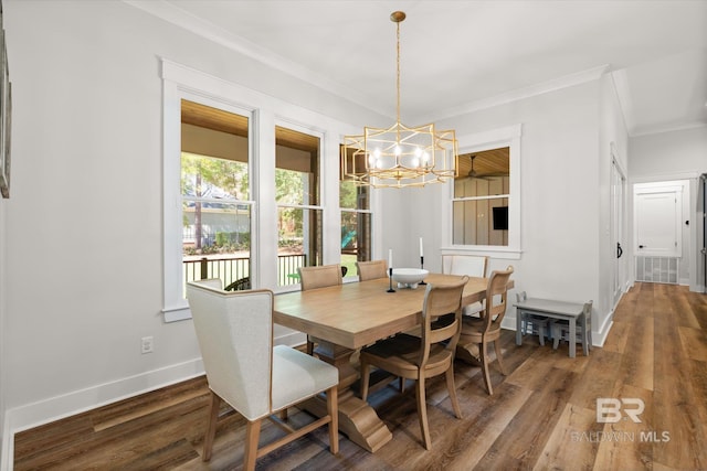 dining space featuring a chandelier, baseboards, wood finished floors, and crown molding