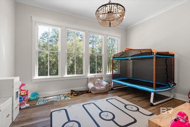 bedroom with baseboards, crown molding, an inviting chandelier, and wood finished floors