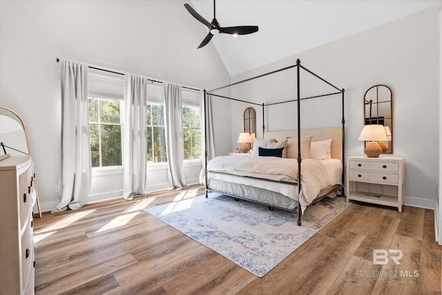 bedroom featuring baseboards, high vaulted ceiling, a ceiling fan, and wood finished floors