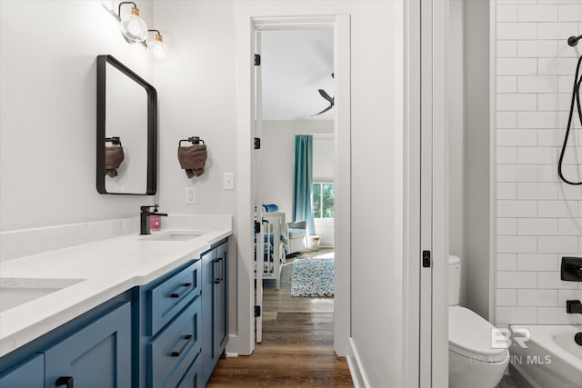 full bath with toilet, double vanity, wood finished floors,  shower combination, and a sink