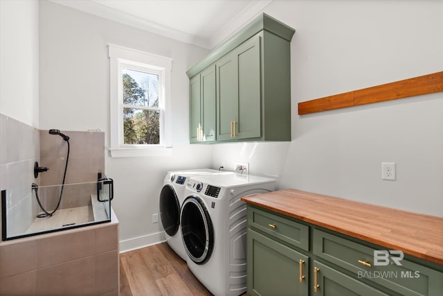 laundry room featuring light wood-style flooring, ornamental molding, washer and dryer, cabinet space, and baseboards