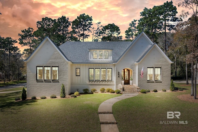 view of front of home featuring brick siding, board and batten siding, and a front lawn