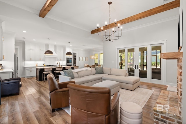 living room featuring an inviting chandelier, beamed ceiling, recessed lighting, and light wood-type flooring