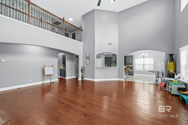 unfurnished living room featuring wood-type flooring, a chandelier, and a high ceiling